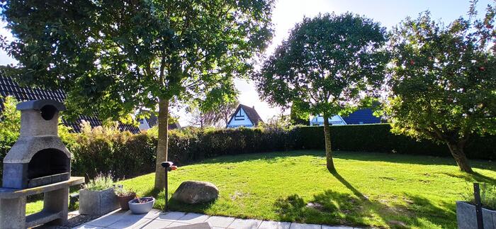 Garten mit Rasen, Bäumen und Grill