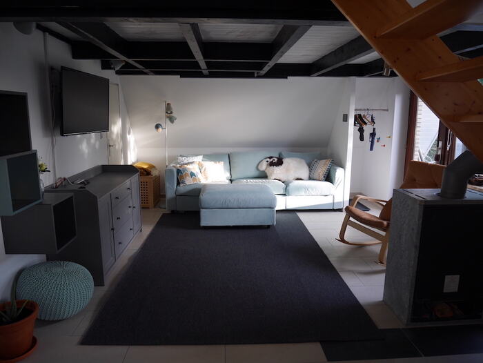 Wohnzimmer mit Sofa, Kaminofen und Treppe